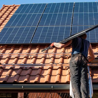 Operatori trasportano pannelli fotovoltaici sul tetto di un'abitazione pronti per essere installati